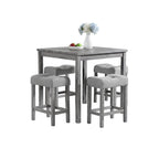 Gray dining table with four matching stools in a room with large windows and decorative elements.